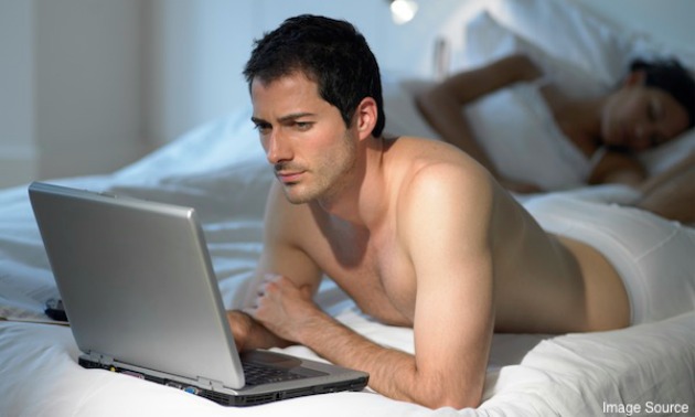 Man using laptop as wife sleeps