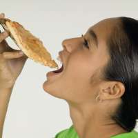 Young girl putting pizza into mouth